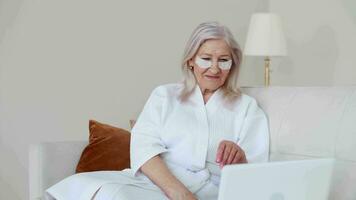 pele Cuidado, Senior mulher, casa cosméticos, idosos idade, Cosmético procedimentos. idosos mulher falando remotamente usando computador portátil durante Cosmético procedimentos video