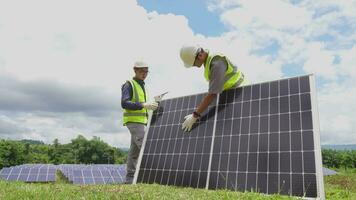 en team av två ingenjörer är arbetssätt till Installera sol- paneler på en sol- kraft station. ingenjör team diskuterar de arbete till Installera sol- celler. tekniker inspektera och reparera sol- celler. video