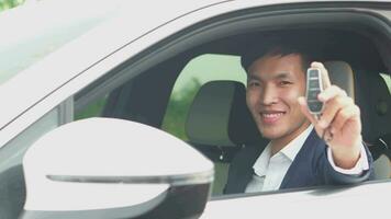 ung asiatisk affärsman som visar en bil nyckel inuti hans ny elektrisk fordon. ev bil. ev fordon. begrepp av grön energi och begrepp minska co2 utsläpp och ung affärsman Framgång. video
