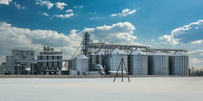 modern agro-processing plant for processing and silos for drying cleaning and storage of agricultural products, flour, cereals and grain in snow of winter field photo