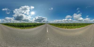 spherical 360 hdri panorama on old asphalt road among corn fields with clouds and sun on blue sky in equirectangular seamless projection, as skydome replacement in drone panoramas, game development photo