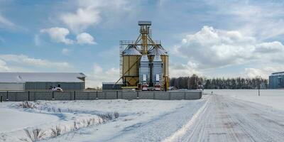 modern agro-processing plant for processing and silos for drying cleaning and storage of agricultural products, flour, cereals and grain in snow of winter field photo