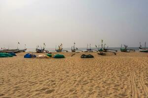 old fishing boats in sand on ocean in India on blue sky background photo