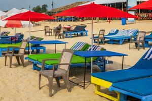 colorful wooden beach umbrellas and sunbeds loungers on sandy beach of ocean photo