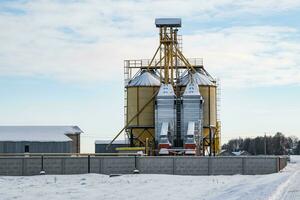 moderno agroprocesamiento planta para Procesando y silos para el secado limpieza y almacenamiento de agrícola productos, harina, cereales y grano en nieve de invierno campo foto