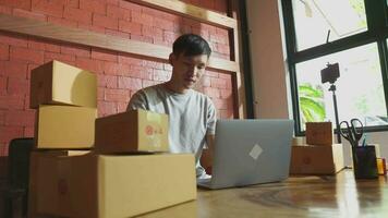 Asia joven comienzo pequeño negocio en un cartulina caja a trabajar. el vendedor prepara el entrega caja para el cliente, en línea ventas, o comercio electrónico video