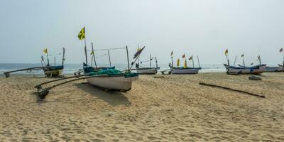 old fishing boats in sand on ocean in India on blue sky background photo