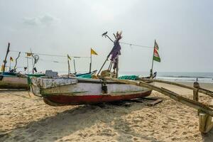 old fishing boats in sand on ocean in India on blue sky background photo