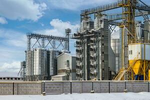 modern agro-processing plant for processing and silos for drying cleaning and storage of agricultural products, flour, cereals and grain in snow of winter field photo