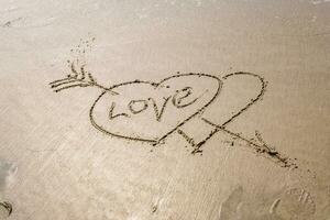 drawing in sand in form of two hearts and inscription love photo