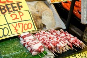 de cerca crudo carne de vaca palo y Mariscos preparar a parrilla y vender para cliente a kuromon mercado, osaka, Japón. foto
