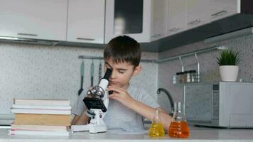 attraente ragazzo insegna biologia utilizzando un' microscopio e fa Appunti nel un' taccuino. compiti a casa. video