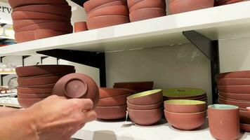 10.16.23 Mississauga Canada. Shopping. A woman holds a plate in a store. Plates are stacked on a shelf in a kitchenware store. Home decor store display with stacks of ceramic plates. video