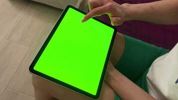 Digital tablet with green screen chromatic keyboard in the hands of a girl. A girl at home orders gifts from an online store. Green screen video. video