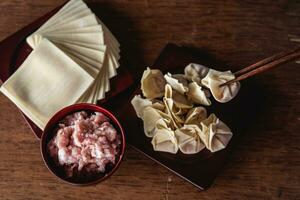 Top view of raw Chinese dumpling and mince pork, ingredient for cooking on wooden table photo