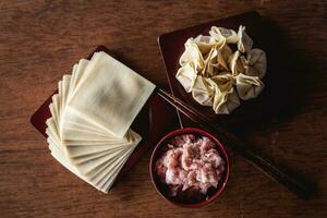 Top view of raw Chinese dumpling and mince pork, ingredient for cooking on wooden table photo