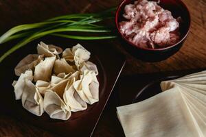 Closed up of raw Chinese dumpling and mince pork, ingredient for cooking on wooden table photo