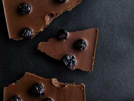 Dark chocolate broken with blueberries on a black background. View from above. photo