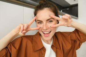 Close up portrait, face of happy woman, enjoying listening to music, wearing wireless headphones, laughing and smiling photo