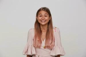 lleno de alegría joven bonito rubia dama con largo pelo demostración su agradable emociones mientras posando terminado blanco antecedentes en papel papel picado, sonriente felizmente mientras mirando a cámara foto