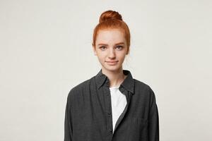 Red-haired student with a bun on her head dressed in a simple black shirt looking at the camera confidently without constraint, isolated on white background photo