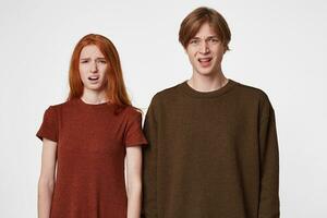 Indoor photo of young guys, boy and girl, look into the camera with an expression of disgust and frustration on their face. How could this happen What a mess, what to do about it