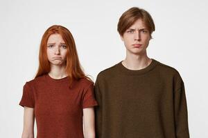 Offended upset little angry young guy and red hair girl isolated on white background looking directly into the camera, dressed casual. photo