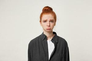 Close up of young sad red-haired girl, she is very upset, frowns eyebrows, lowered her lower lip, looks lamentable. The girl is offended because she did not get a gift. photo