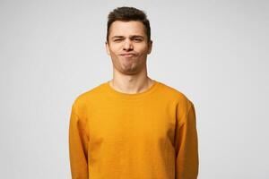 Studio shot of a young guy standing confident, chin up, on the face expression of a success, winning, show class, winner, pleased enjoying himself, isolated over white background photo