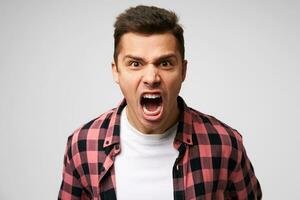 Furious,enraged man with grumpy grimace on his face,with mouth opened in shout, ready to argue and swear, wants to gain respect, show strength, isolated over white background photo