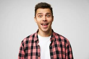 Horizontal shot of shocked young male, expresses great surprised. Mouth and eyes are widely opened, isolated over white background. Positive successful young man has overjoyed expression photo