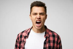 Angry, irate man with grumpy grimace on his face,with mouth opened in shout, ready to argue and swear, wants to gain respect, show strength, isolated over white background photo