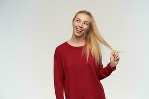 Portrait of attractive, adult girl with blond long hair. Wearing red sweater. People and emotion concept. Watching to the left at copy space, isolated over white background photo