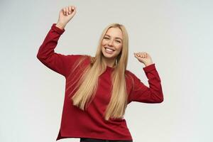 Adolescente chica, contento mirando bailando mujer con rubio largo cabello. vistiendo rojo suéter. personas y emoción concepto. acecho a el cámara, aislado terminado blanco antecedentes foto