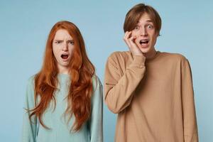 Close up couple, looking at the camera with stunned offended shocked facial expression as if they saw something inappropriate immoral beyond the limits of propriety,isolated on a blue background photo
