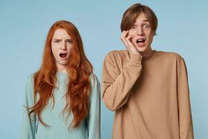 Close up couple, looking at the camera with stunned offended shocked facial expression as if they saw something inappropriate immoral beyond the limits of propriety,isolated on a blue background photo