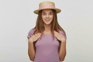 Beautiful female with amazed expression, looks with bugged eyes and keeps mouth open, indicates at herself with both palms, isolated over white background. Human reaction and emotions concept photo