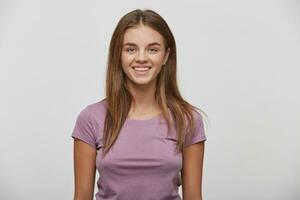 retrato de un hermosa alegre contento joven niña con natural maquillaje y bien arreglado cabello, sonrisas, usa casual t camisa, en un blanco antecedentes en el estudio. foto