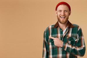 Perky and cheerful happy interesting bearded guy smiles broadly and laughs, shows with his index finger to the left to an empty space for advertising. photo