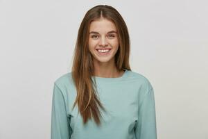 Portrait of a beautiful cheerful happy young girl with natural make-up and well-groomed hair, smiles, wears casual blue long sleeve t-shirt, on a white background in the studio. photo