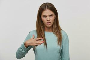 Shoot of a beautiful young girl expressing misunderstanding, hand straightens hair, frustrated annoyed woman confused, dressed casual, on a white background in the studio. photo