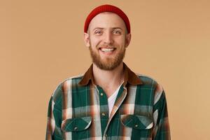 Attractive bearded man in red hat being very glad smiling with broad smile showing healthy teeth having fun indoors. Joyful excited male rejoicing after pleasant meeting photo