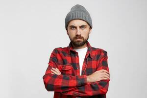 Upset unhappy young man over white background. An angry, terrible, serious man stands with his arms crossed in front of him and expects an apology or concrete action from the one who has done it. photo