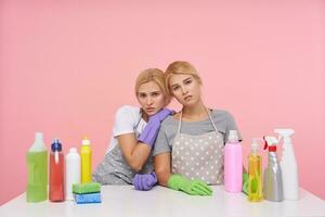 Unhappy young pretty white-headed housewives with casual hairstyle frowning eyebrows while looking sadly at camera, being exhausted after cleaning big house photo