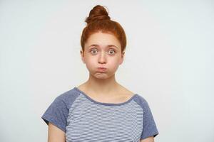 Agitated young pretty redhead woman taking air in her mouth and looking excitedly at camera with wide eyes opened, standing against pink background in casual t-shirt photo