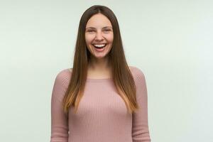 Close up portrait of happy female laughs at something funny, has positive expression, has brown long hair down, dressed casually, feels happiness, isolated on white photo