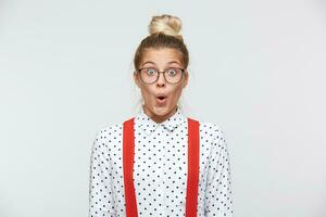 Surprised facial expression. Have look at that amazing thing Portrait of shocked female lowered jaw from surprise, feels stupefied, being impressed by something. In a white shirt, red suspenders photo