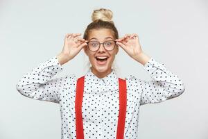 Portrait of a young woman holding glasses and looking at camera. Health and vision concept - joyful woman adjusting eyeglasses, feeling happy with diopters selection. Poor eyesight, vision concept. photo