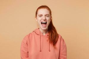 Negative emotions and feelings.Emotional red-haired lady feeling violent emotions, opening her mouth widely screaming loudly being dissatisfied with something expressing disagreement and annoyance photo