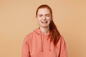 retrato de un Pelirrojo atractivo niña quien es llorando sufre desde no correspondido amar, porque de un roto teléfono, un perdido billetera, vestido en el usual ordinario camisa de entrenamiento foto